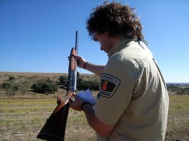 Agente forestal inspeccionando una escopeta de caza.
